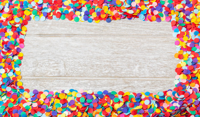 Background for carnival, New Year - colorful, round confetti as a frame on wood