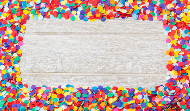 Background for carnival, New Year - colorful, round confetti as a frame on wood
