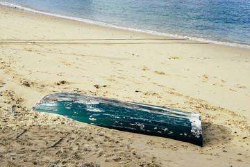 Inverted boat on deserted beach near water