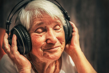 old woman in headphones listening to music