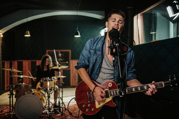 Music band having rehearsal in a studio