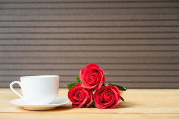 Red rose and coffee cup on wood