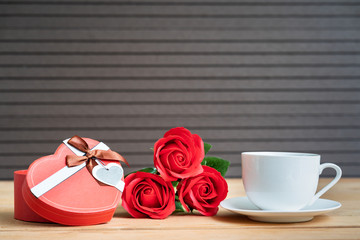 Red roses and gift box on wood background