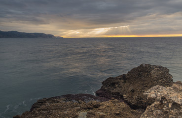 Nerja, Malaga, Andalusi, Spain - November 25, 2018: Long exposure on the coast with a rocks in the foreground under a stormy sky