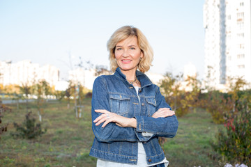 Obraz premium Portrait of a mature woman against the background of the city and blue sky.