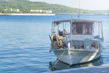 Fototapeta na wymiar Small white overloaded fishing boat anchored next to the dock