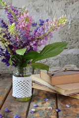 Pink, purple lupine flowers bouquet in vase and old book. Birthday, Mother's day, Valentine's Day, March 8, Wedding card or invitation. Festive Floral decorative background. Copy space