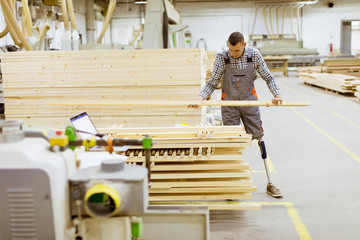Disabled young man with an artificial leg is working at the furniture  factory