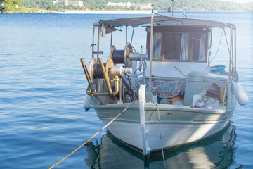 Small white overloaded fishing boat anchored next to the dock