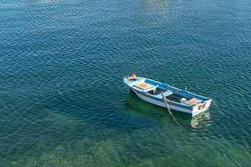 Small white blue boat with paddles anchored on the shore