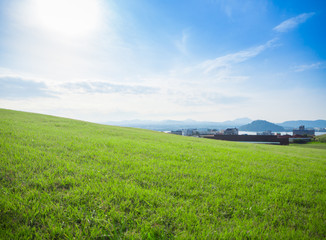Fototapeta premium Green grass fields on the hills Overlooking the sea, mountains and beautiful sky