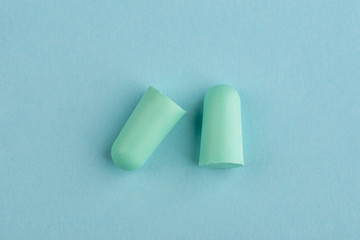 Green earplugs on blue background