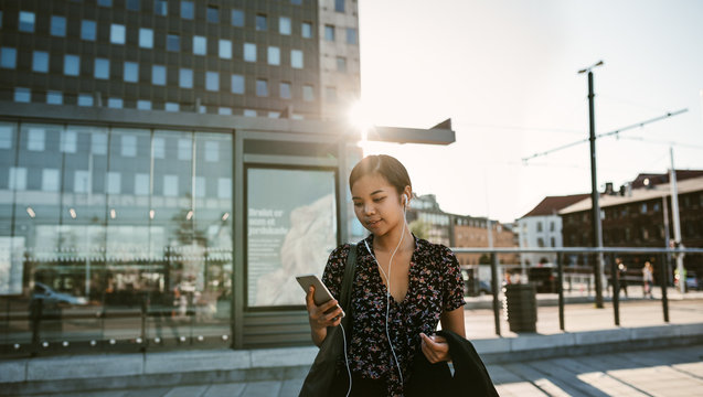 Young Asian businesswoman listening to music during her morning commute