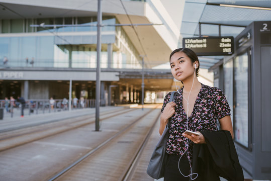 Asian businesswoman waiting for a tram during her morning commute - Powered by Adobe
