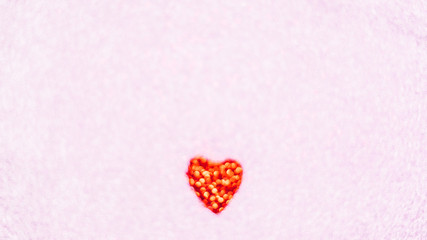 Blurred glowing red glitter heart on pink background