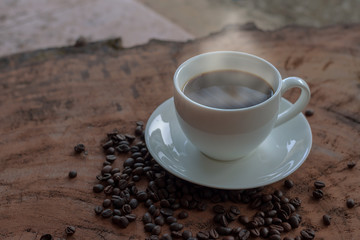 Coffee in a white cup and coffee beans on a wooden table