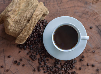 Coffee in a white cup and coffee beans on a wooden table