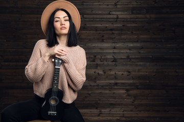 Pretty young woman hugging her guitar, dressed in country style