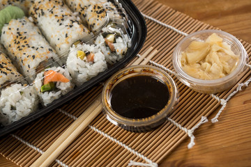 Inside Out Sushi vom Lieferdienst in Variation Lachs, Mango, Avocado mit Ingwer und Soja Soße in Einweg Plastik Bento Box Verpackung