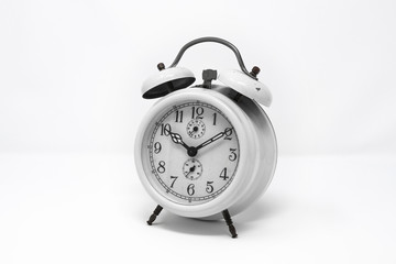 old white analog twin bell alarm clock isolated on a white background. Vintage metal object, ruined by time. Wake up early in the morning to the sound of the bell.