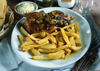 Plato con medio pollo al grill, con patatas fritas.