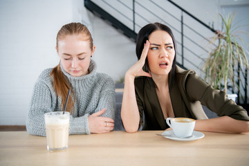 Two young women argue in cafe. Emotional speech