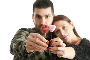 Young couple holding glitter hearts as a symbol of their love, studio shot isolated on the white background
