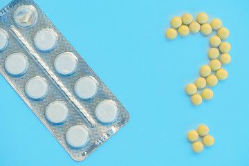 White and yellow pills on the blue background .