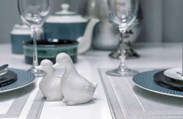 Ceramic salt shakers in the form of ducks in the interior of a modern dining room.