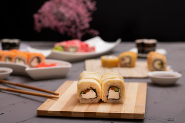 asian sushi rolls with sauce and chopsticks, sakura flower and blurred background