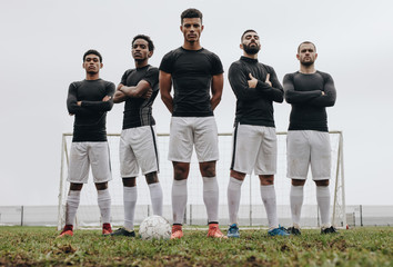 Footballers standing side by side on a soccer field