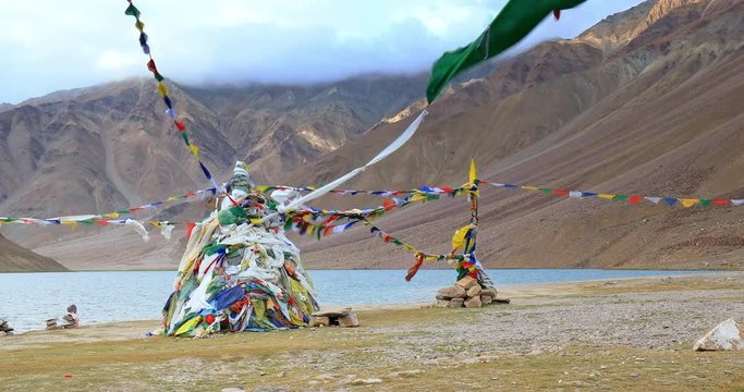 Buddhist Stupa decorated with colorful prayer flags on shore of Chandra Taal lake in Himalaya mountains, north India