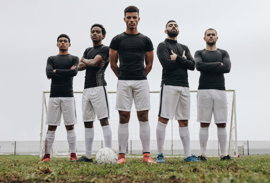 Footballers standing side by side on a soccer field
