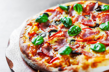 Pizza with Mozzarella cheese, ham, pepper, olive, meat, Tomato sauce, Spices and Fresh Basil. Italian pizza on wooden background