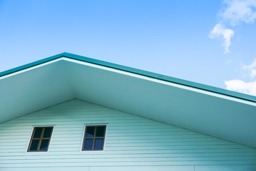 Symmetric detail shot of green roof gable showing ventilation panel with blue sky