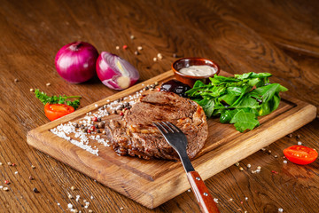 Italian cuisine. Juicy beef meat, veal steak on a wooden board with spinach, prunes and French...