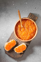 Red caviar on a wooden Board on a gray table. Top view