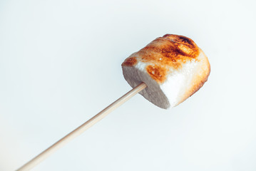 roasted marshmallows on a skewer on white background