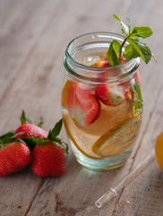 Fresh drink with strawberries, lemon and mint. Serving on a wooden table