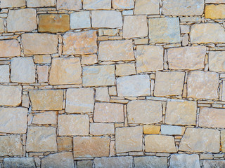 Texture of yellow concrete wall with large and small bricks in mozaic pattern
