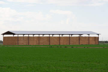 Building with bales of hay surrounded by green fields