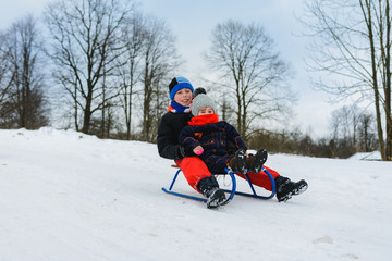 Fototapeta na wymiar boy and girl are riding on sleds