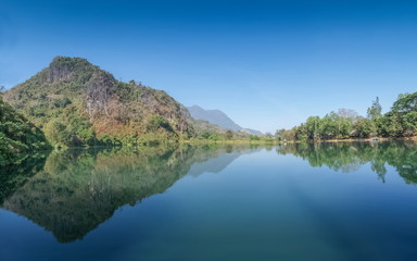 Naklejka premium Tham Sao Hin Payanak Reservoir, Lake view of bamboo bridge cross reservoir with mountain and blue sky background, Wat Tham Sao Hin Payanak, Mae Sai District, Chiang Rai, Thailand.