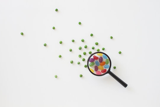 View through a magnifying glass of Peas turning into  jellybeans 