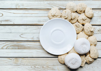Top view on white dish, Meringue, Marshmallow, Zephyr wooden background. Flat lay. Pastry concept, copy space. Rustic. Zephyr.
