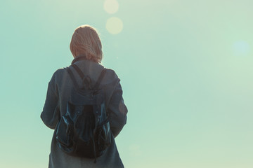 A woman is standing with her back turned against the sky. The concept of female loneliness,...