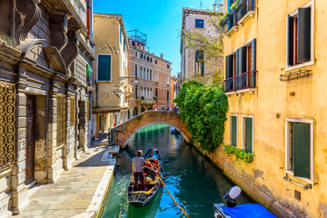 Narrow canal with gondola and bridge in Venice, Italy. Architecture and landmark of Venice. Cozy cityscape of Venice.