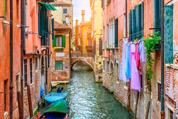Narrow canal with boat and bridge in Venice, Italy. Architecture and landmark of Venice. Cozy cityscape of Venice.
