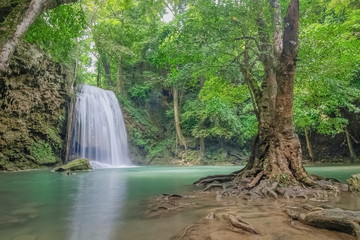 Fototapeta na wymiar Erawan Waterfall, beautiful silky water flowing on arch rock around with green forest background, floor 3th Erawan waterfall, Kanchanaburi, Thailand.