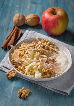 Grated apple with walnut and yogurt on blue table